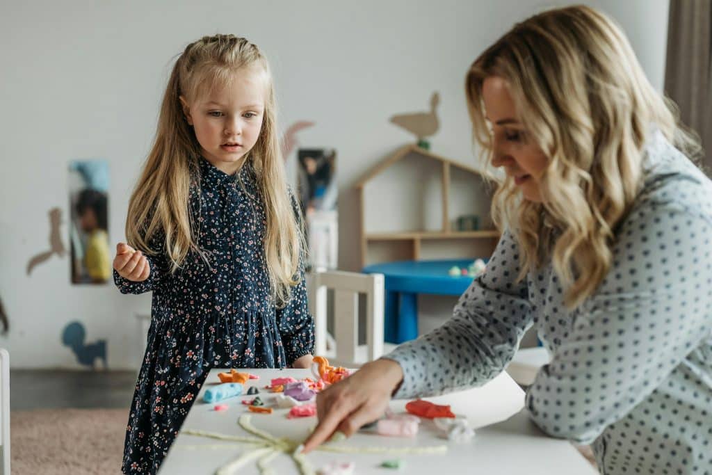 Stagiaire travaillant dans une crèche avec une enfant après avoir réalisé une formation dans la santé et le social.