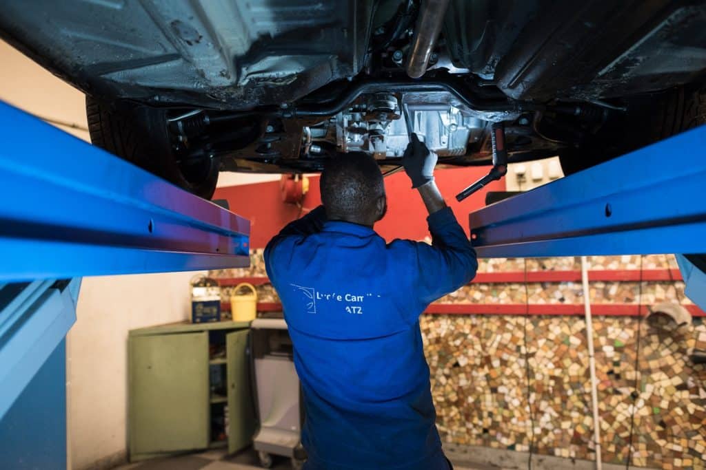 Stagiaire mécanicien automobile réparant une voiture montée sur un pont dans le cadre du Titre Pro Mécanicien de Maintenance Automobile du Greta GPI2D.